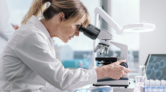 Lab tech looking through a microscrope.