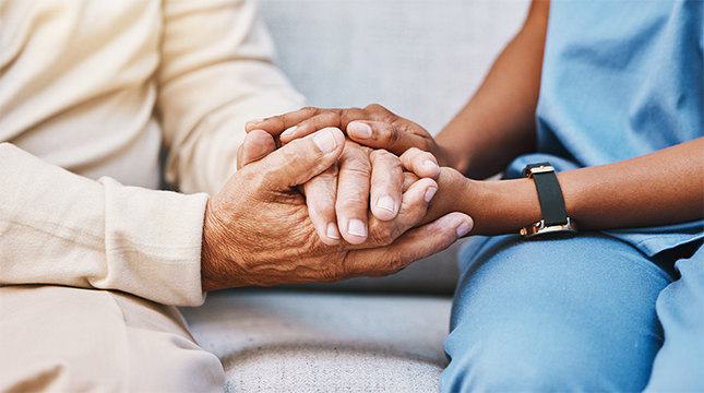 Nurse holding a patient's hands.